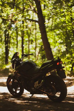 Stüdyodaki gri duvarın arka planında spor siyah motosikleti var..