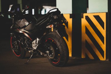 Yeraltı otoparkının arka planında siyah motosiklet.