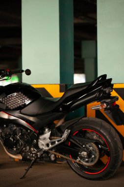 Yeraltı otoparkının arka planında siyah motosiklet.