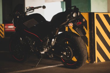 Yeraltı otoparkının arka planında siyah motosiklet.