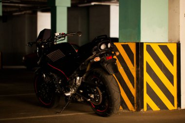 Yeraltı otoparkının arka planında siyah motosiklet.