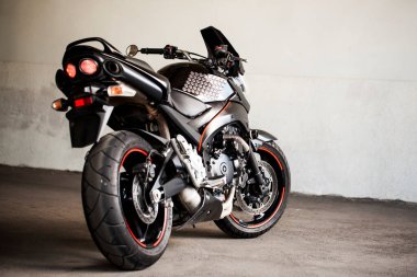 Yeraltı otoparkının arka planında siyah motosiklet.
