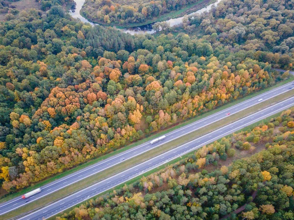 Vista aérea de los colores otoñales en el bosque con carretera y río cruzándolo — Foto de Stock