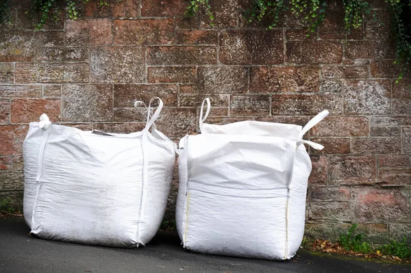 Aggregate white sacks full of gravel on street outside house — Stock Photo, Image