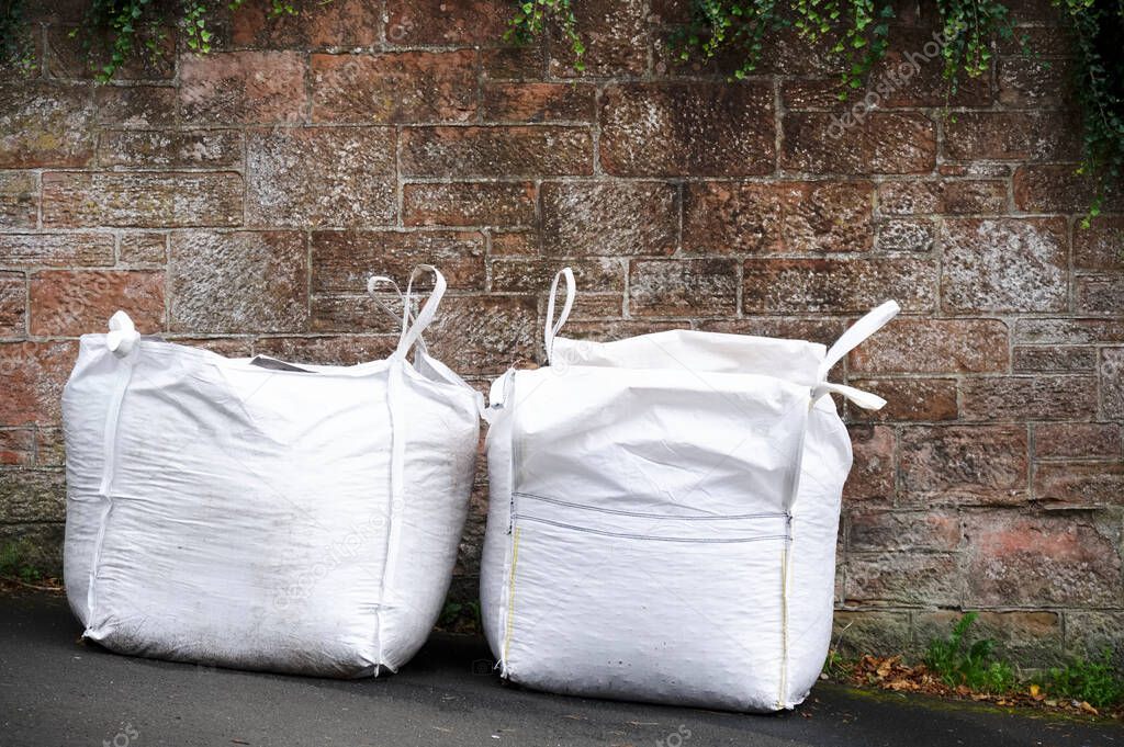 Aggregate white sacks full of gravel on street outside house