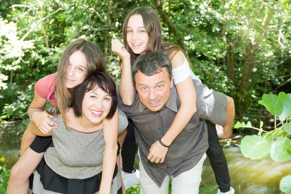 family of four piggyback daughter twins sister in garden park summer love
