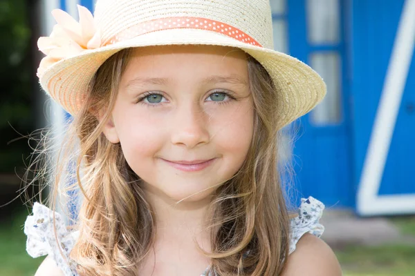 漂亮的孩子女孩用草帽前木蓝色房子春天天 — 图库照片