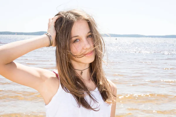 pretty teenager girl with hair blowing on wind next to the sea