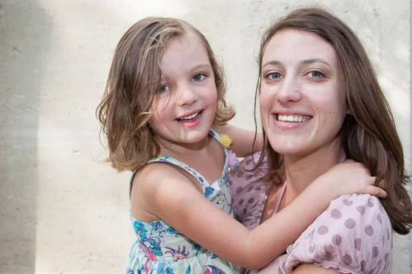 Schöne Mutter Und Tochter Umarmen Sich Vor Wandhintergrund — Stockfoto