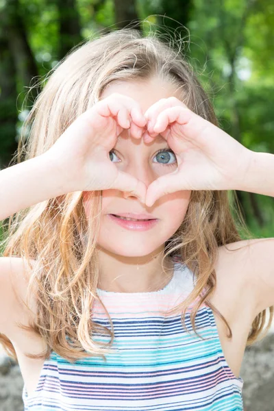 Jovem Menina Bonita Faz Coração Com Dedos Frente Seu Rosto — Fotografia de Stock