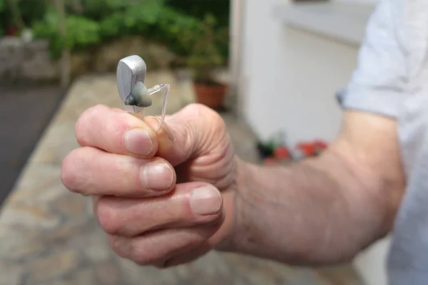 closeup hand Man holding hearing aid on blurred background