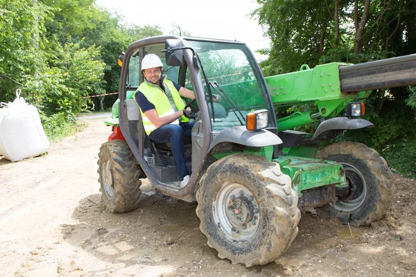 Excavator driver man operator with metal tracks unloading soil at construction site