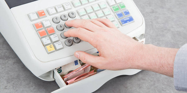 Nearly empty cash register on table from top view with man hands