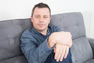 Genç adam evde kanepe rahatlatıcı portresi