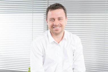 Kameraya bakarak ve office iş yerinde gülümseyen mutlu adam işadamı