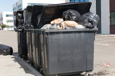 sokakta tam ve çöp torbası ile taşan üç büyük gri depo gözleri