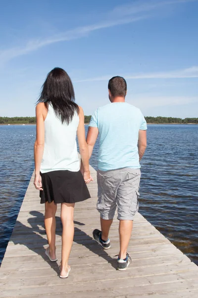 back view of happy young couple in love in pontoon bridge on lake