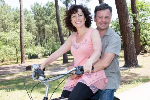 couple riding two on bike like a tandem bicycle