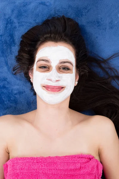 beautiful woman at the center of well being with a clay mask on her face