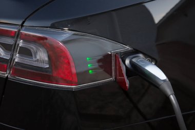 yüklenmekte olan bir hibrid otomobil elektrik fişini hızlı bir stop sokakta vardır.