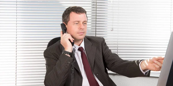 電話で顧客とコンピューター作業のスーツのビジネスマン — ストック写真