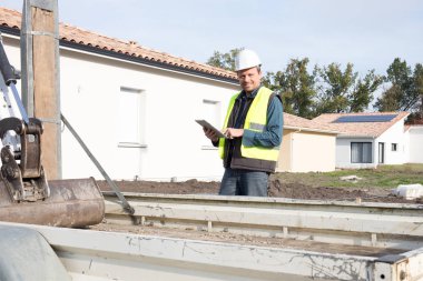 İnşaat alanında koruyucu ekipman kask giyiyor tablet ile Mimar adam mühendisi