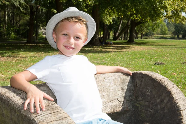 Menino Loiro Alegre Sentar Banco Madeira Parque Com Chapéu Verão — Fotografia de Stock