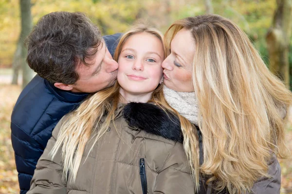 Family playing kiss daughter blond in autumn park having fun