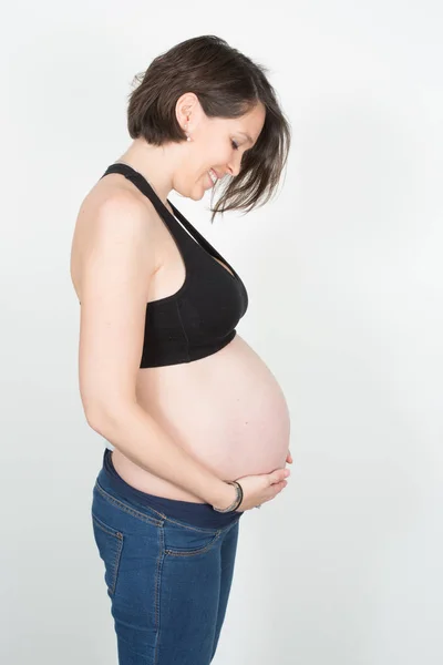 美丽的怀孕妇女爱抚她的腹部在白色背景 — 图库照片