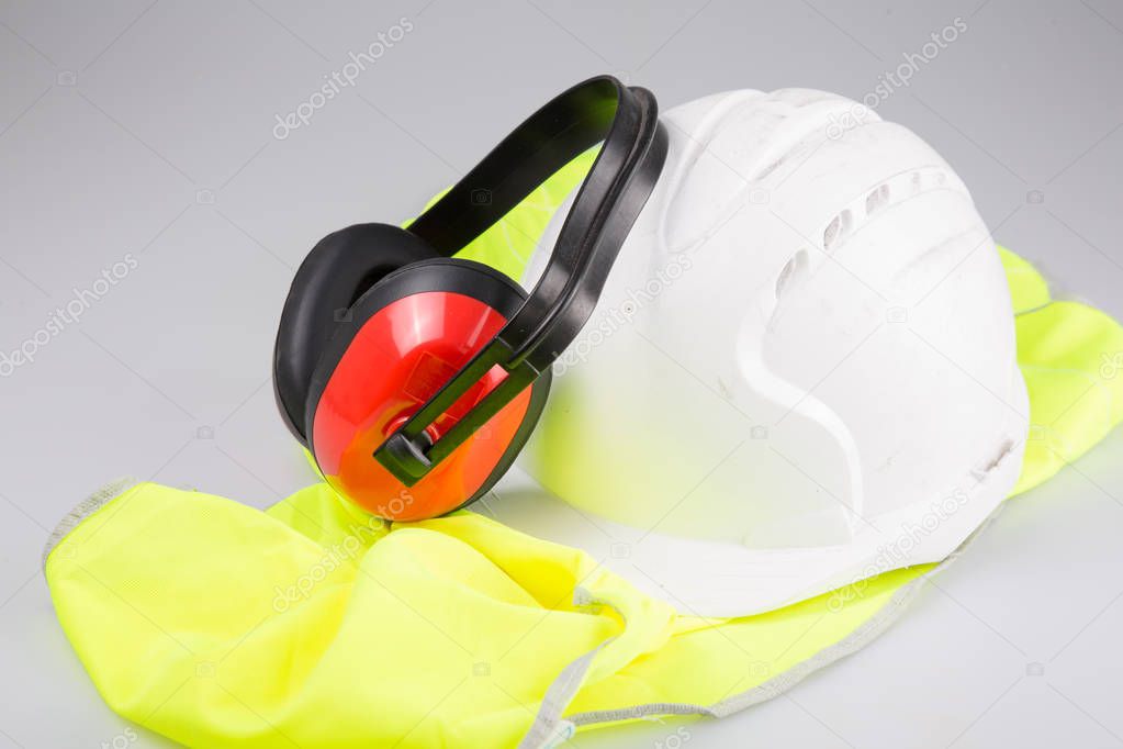 white helmet ear muffs placed on yellow vest with Reflective on white background in safety work concept