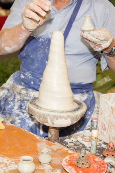Craftsman making vase ceramic pot from fresh wet clay on pottery wheel