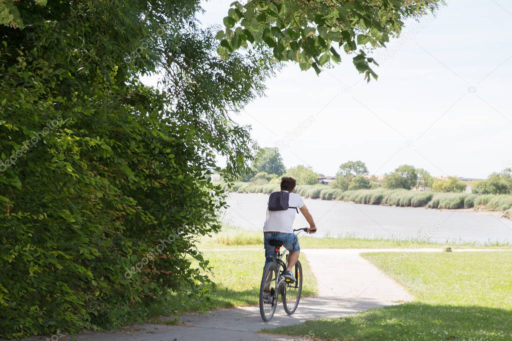 man riding a bicycle on the bike path next to the river during holidays