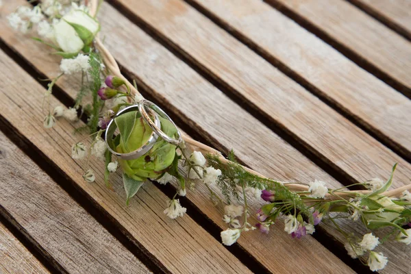 Wedding rings on a flower headband on a wooden table