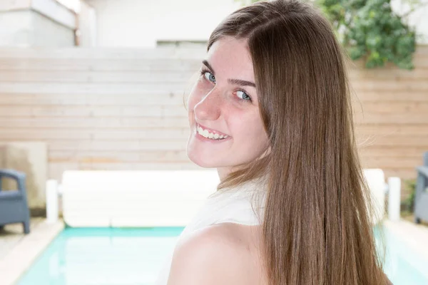 立っていると 夏のプールに笑みを浮かべて白いドレスで陽気な素敵な若い女性 — ストック写真