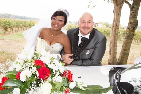 interracial american couple african bride posing on wedding car with caucasian groom