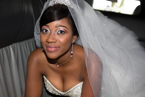 Beautiful young black bride looks at the camera and smiles in wedding car