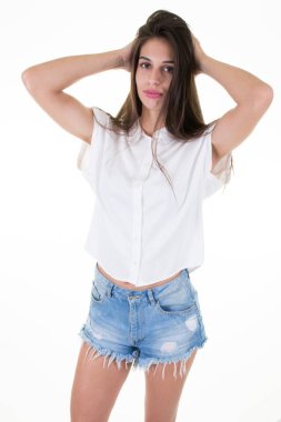 Mutlu güzel esmer genç kadın uzun saçlı portresi gömlek giyer ve gülümseyen ve beyaz arka plan üzerinde izole ayakta kot şort