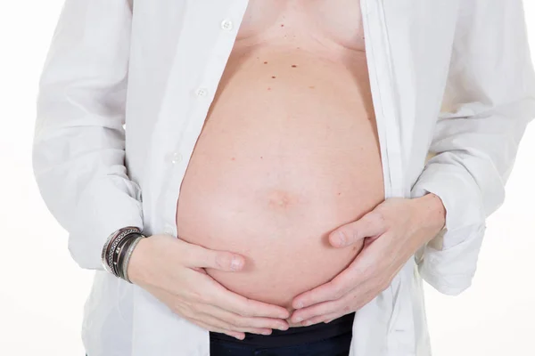 妊娠中の女性と彼女の腹に触れるの正面の白い背景の手します — ストック写真