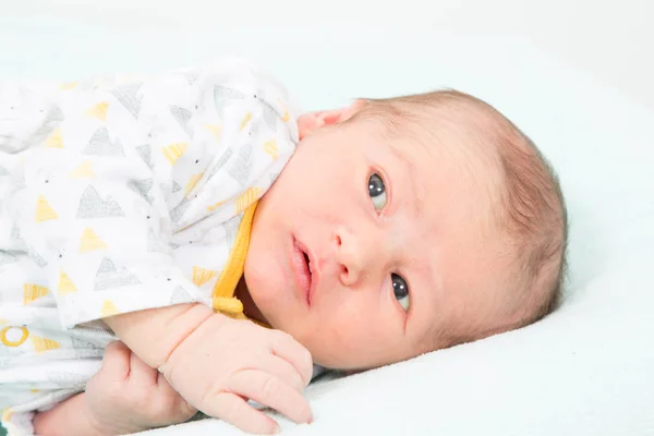 新生儿看起来担心在清晰的白色柔软的床背景 — 图库照片