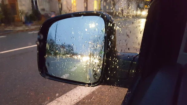 Regentropfen Auf Kotflügel Autospiegel Mit Abstrakter Unschärfe Von Lichtverkehr Und — Stockfoto