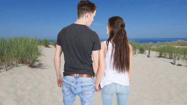 back view of young couple in dunes beach sand and ocean