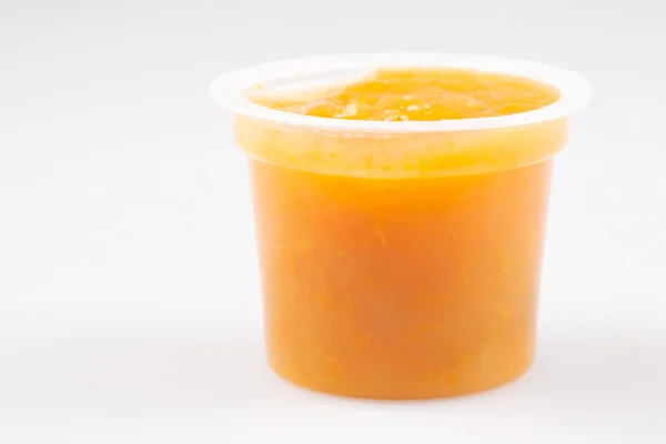 Orangen Aprikosenkompott Plastikglas Auf Weißem Hintergrund — Stockfoto