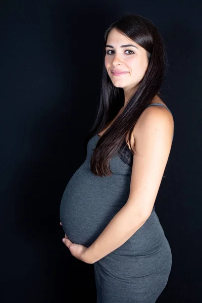 Schwangere Berührt Bauch Vor Schwarzem Hintergrund — Stockfoto