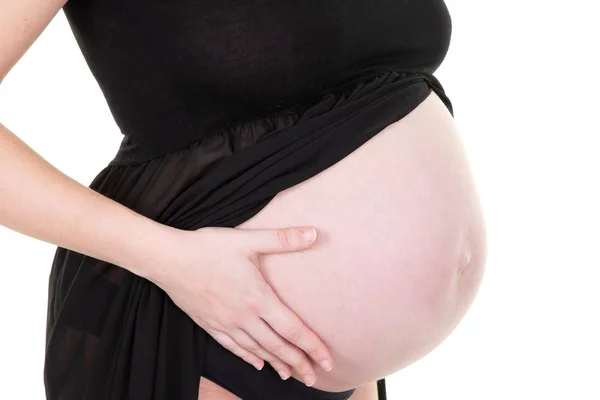 孕妇爱抚她的肚子在白色背景的黑色礼服 — 图库照片