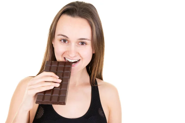 かなり陽気な女性のスポーツが写真の肖像画で孤立した白い背景バー チョコレートを食べる — ストック写真
