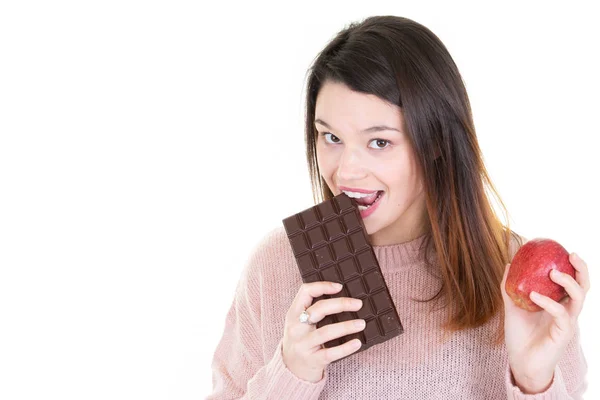 フルーツとチョコレートの誘惑されているが健康になろうとして若い女性 — ストック写真