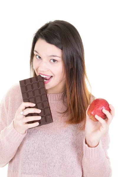 赤いリンゴを押しながらバーのチョコレートを食べる女 — ストック写真
