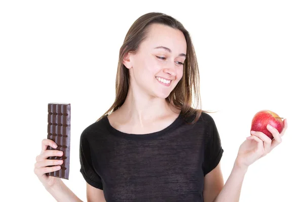 赤いリンゴとチョコレートバーを持つかなり若い女性は 健康になろうと誘惑 — ストック写真