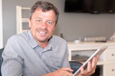 evde tabletini kullanan yakışıklı orta yaşlı adam gülümseyen