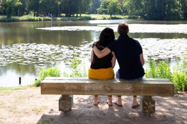 Göl kenarında bankta oturan arka görüş çift
